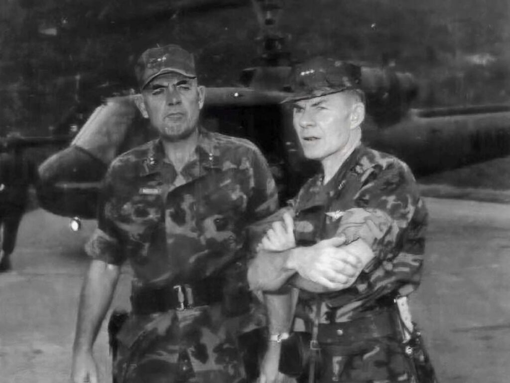 An attack helicopter warms up in the background as Gen. McCutcheon surveys the situation six miles southwest of Da Nang, March 17, 1970, his trusty Randall Model 15 Airman sheathed at his side. At left is Gen. Edwin B. Wheeler.