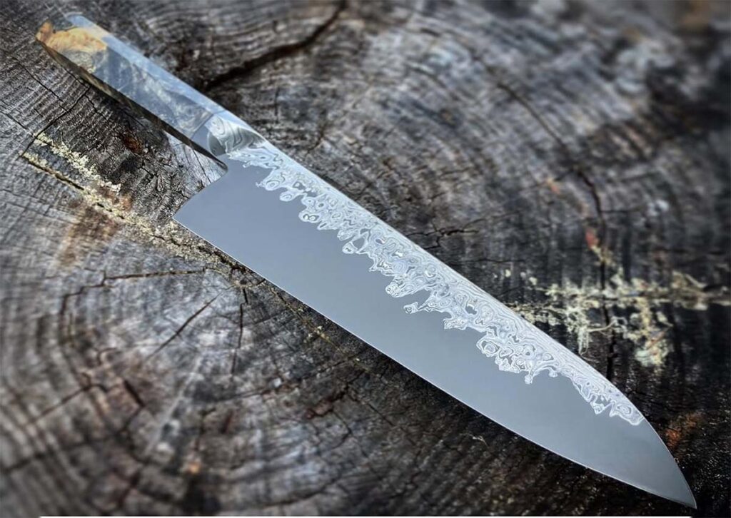 Mareko Maumasi’s gyuto chef’s knife in a san-mai construction serves as the model for the knife second from right at top in the artwork for the BLADE Show Beer.