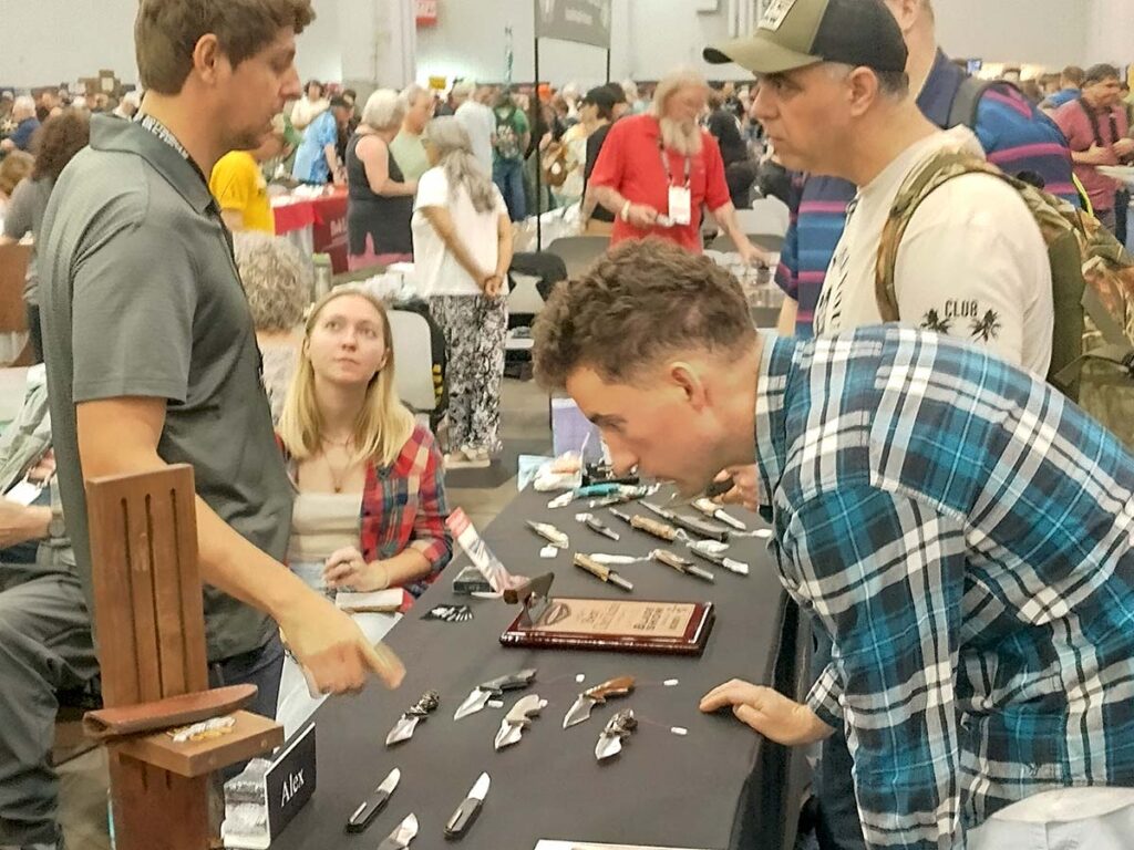 It’s easy to get mesmerized by knives at the BLADE Show, here at the table of Alex Hossom (left).