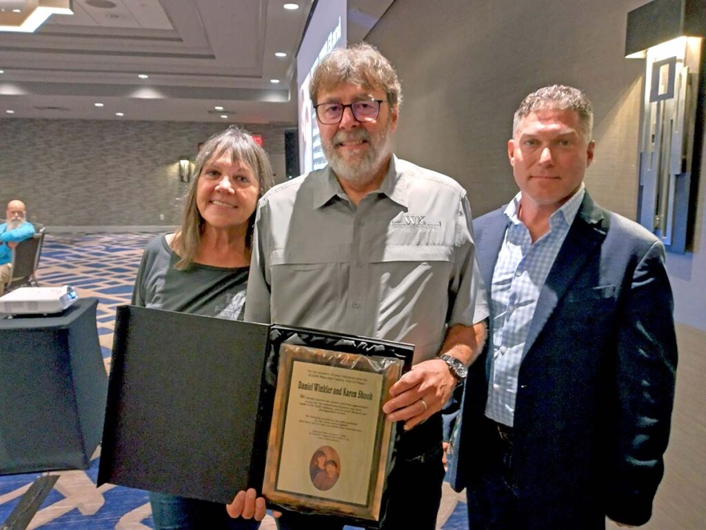 From left, Karen Shook and Daniel Winkler accept their Hall of Fame plaque after Kevin Holland (right) delivered their induction speech.