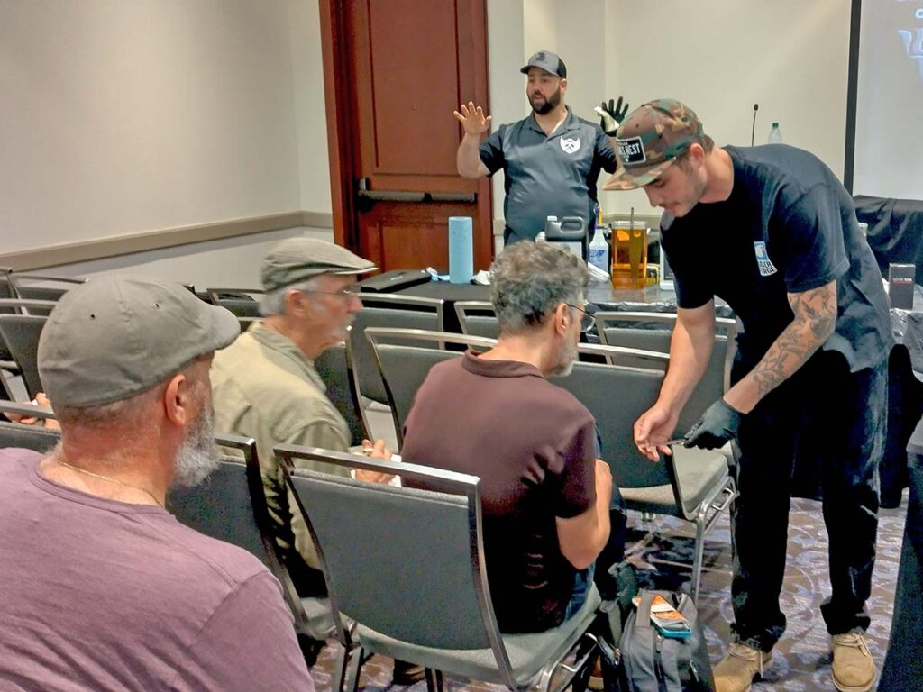Jordan Berthelot discusses next-level damascus etching while Greyson Weltyk shows a student a result of the process during one of many BLADE University classes.