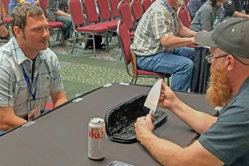 Luke Swenson inspects a patron’s knife at last year’s show.