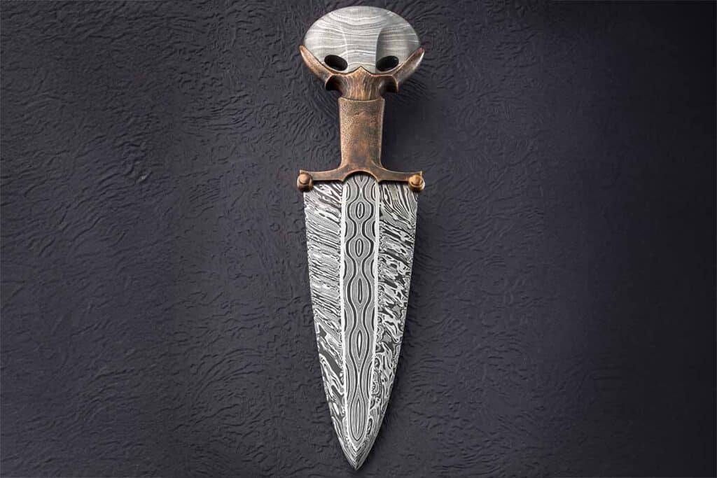 Ryan Breuer, 26, said the primary influence on his one-of-a-kind Relic Dagger is the Bronze Age Egyptian dagger. The shapes on the quillons of Ryan’s knife are carvings in the bronze. While Ryan has made knives for about 10 years, he did not start making them seriously until about eight years ago after graduation from high school. A part-time bladesmith, he works full time as an engineer for a manufacturer making parts for medical devices. (image of Ryan’s knife by SharpByCoop.com)