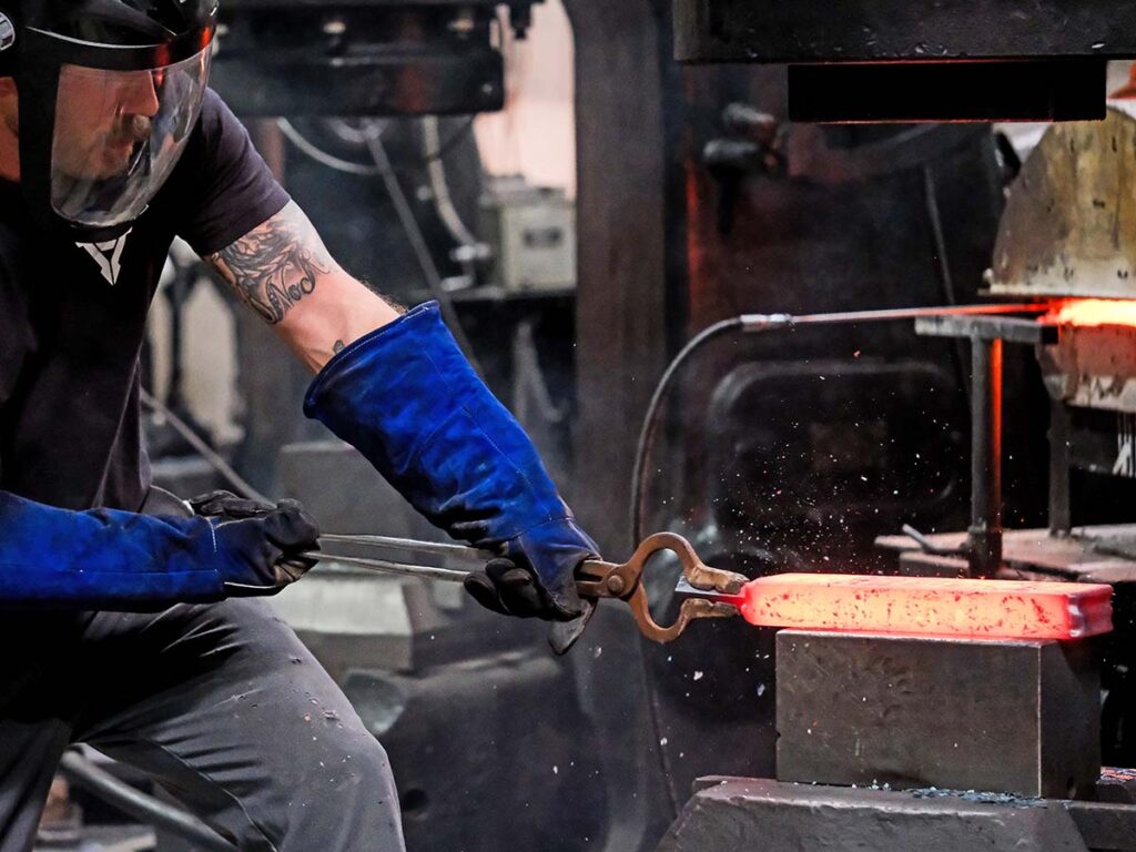 Vegas Forge team member Franklin draws out a 40-pound canister of stainless Raindrop-pattern damascus on the company’s 5B Nazel hammer.