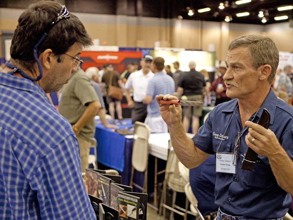 Steve Randall said most makers would not intentionally sell a knife knowing it had a flaw or without first pointing it out to the buyer. Gene Osborn (right) discusses a damascus knife with a customer at a past BLADE Show. (Eric Eggly/PointSeven image)