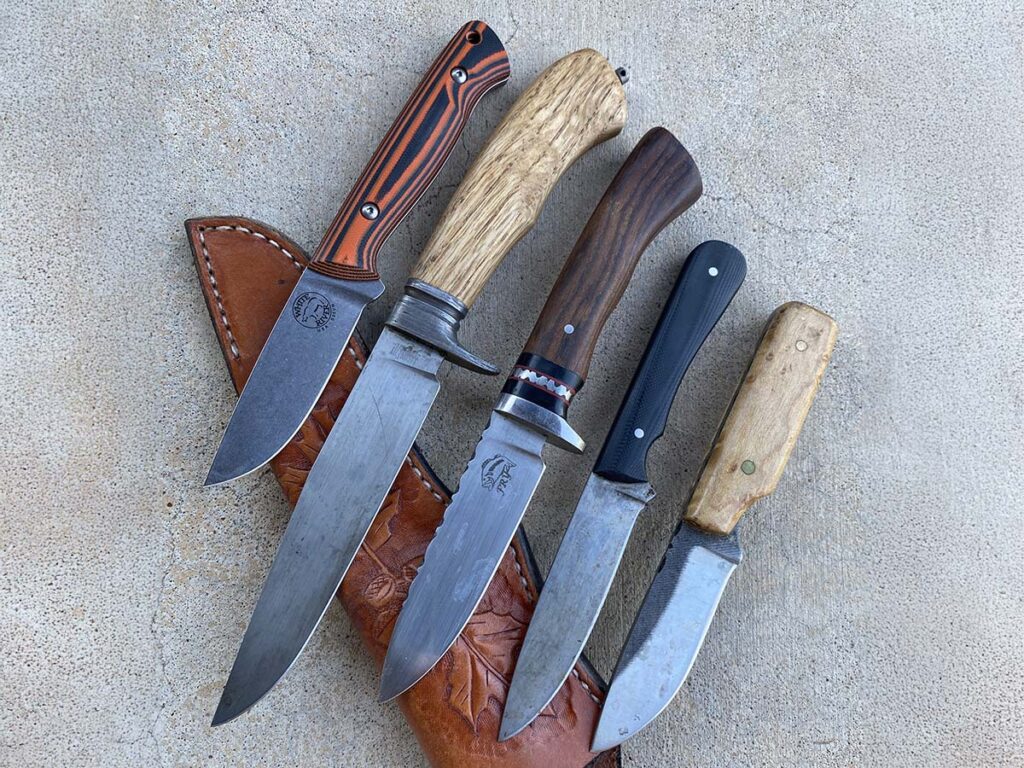  Knives the author has designed and/or made over the years, from left: his Jason Fry Hunter for White River Knife & Tool; his first real forged knife; the 100th knife he ever made, circa 2010; the 50th knife he ever made; and his first-ever knife, the Deer Disassembly Device, aka Triple D. For the knives’ grinds, edge thicknesses and other specs, see the story.