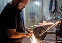 Knifemakers’ Guild voting member Alex Harrison hollow grinds a blade in his shop.