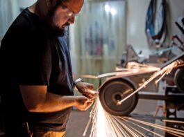 Knifemakers’ Guild voting member Alex Harrison hollow grinds a blade in his shop.