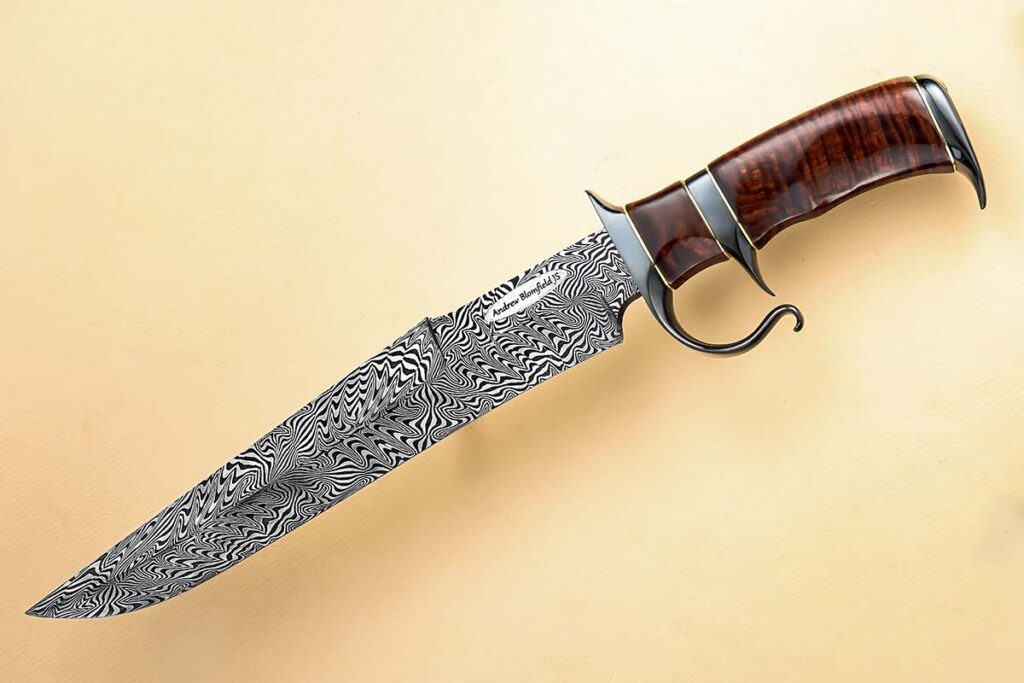 ABS master smith Andrew Blomfield’s sub-hilt bowie is a tour de force of explosive mosaic damascus, salt-blackened steel, brass spacers, and exquisite Australian ringed gidgee wood. Blade and overall lengths: 11 and 16 inches. (SharpByCoop knife image)