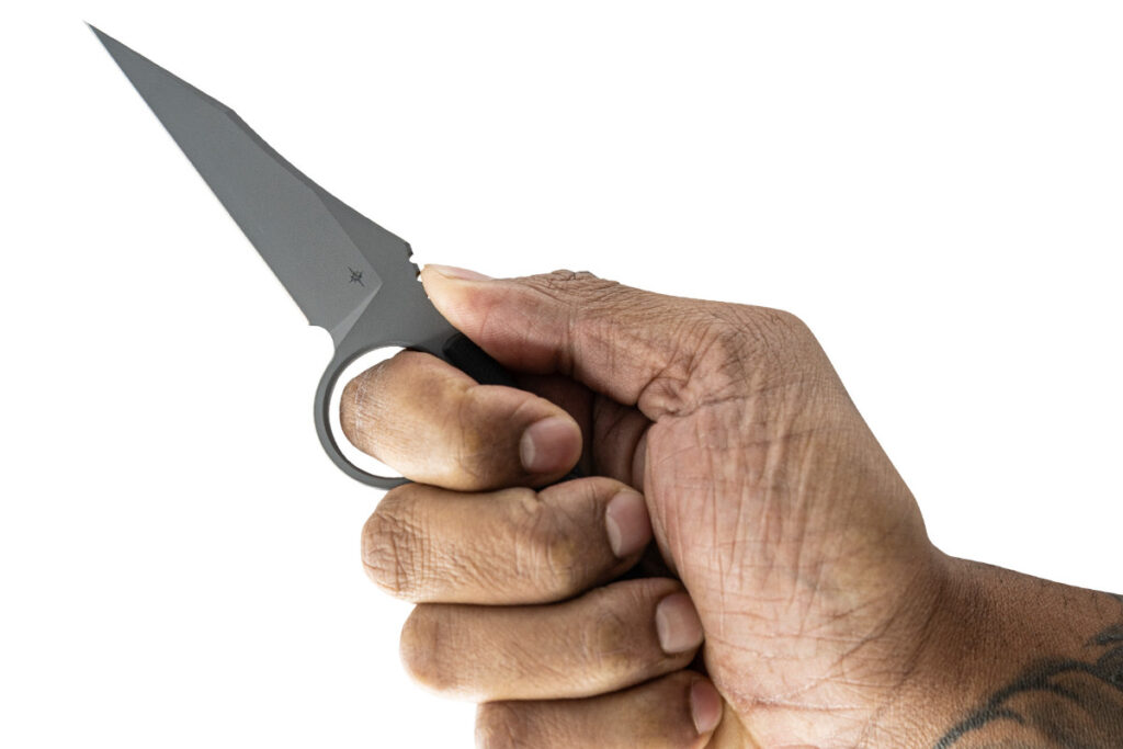 Toor Knives CEO Connor Toor says the hole/ring of the Cortano is between the handle and blade for several reasons, including deployment and retention, a tactile index for consistent hand placement, a lanyard attachment point, and an unmistakable visual signature. Another is the ability to choke up for precise cuts without losing control.