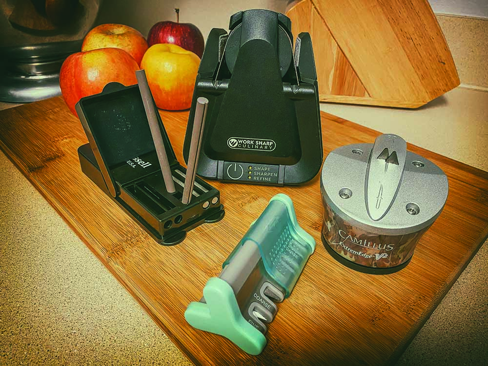 Some of the latest in kitchen knife sharpeners, clockwise from left: A.G. Russell Field Sharpener, Work Sharp Culinary E5, Camillus Extreme Edge V2 Knife & Shear Sharpener, and Smith's Products Slide Sharp Edge Grip 4 Slot Sharpener.