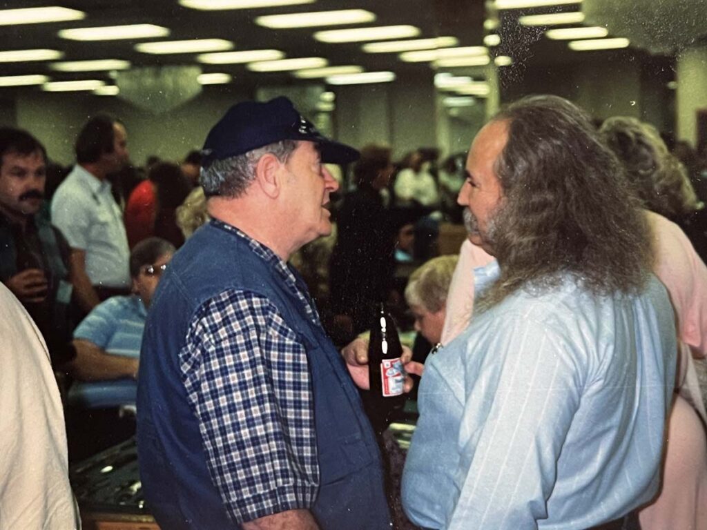Bob Loveless (center) talks with David Crosby (right) of Crosby, Stills and Nash at the 1989 California Custom Knife Show. The two were good friends, with Loveless an inveterate harmonica player who at times would play with CSN at a local bar or night club. At left is a young, mustachioed Steve D’Lack, coordinator today of the New York and Nashville Custom Knife Shows. (John Denton image)