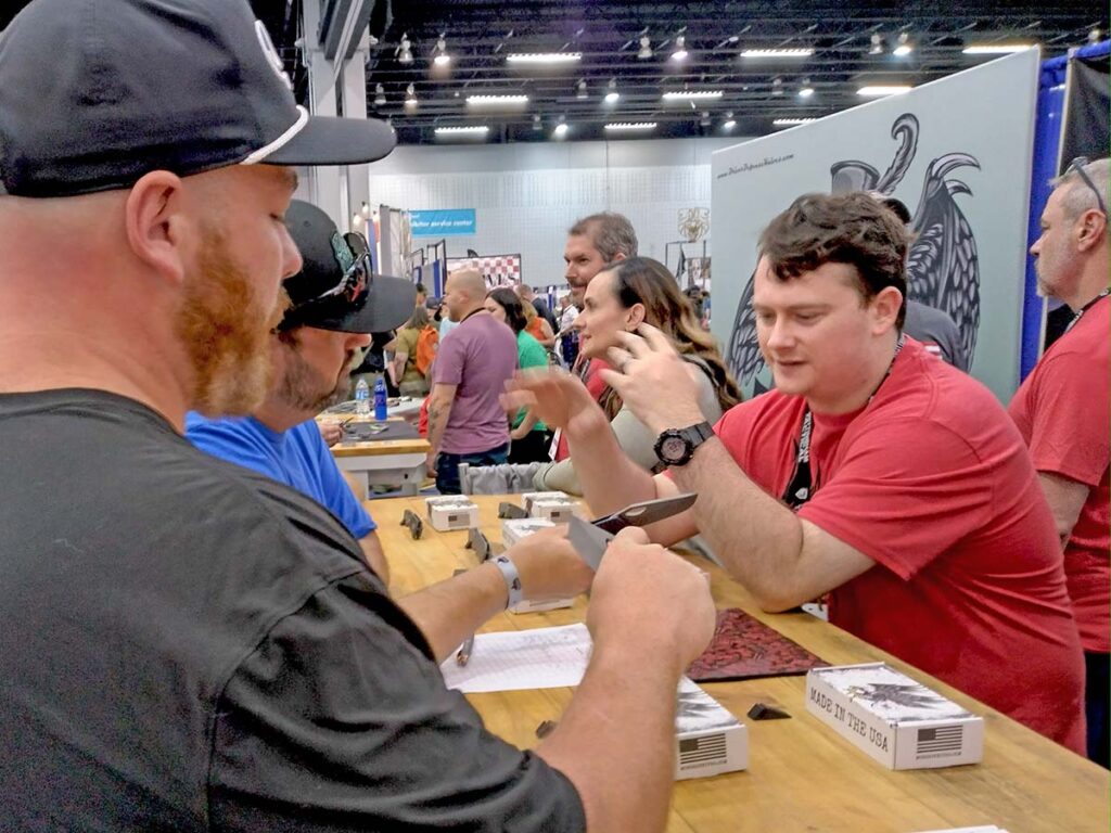 Two blade enthusiasts try out/talk knives at the McNees Knives booth.