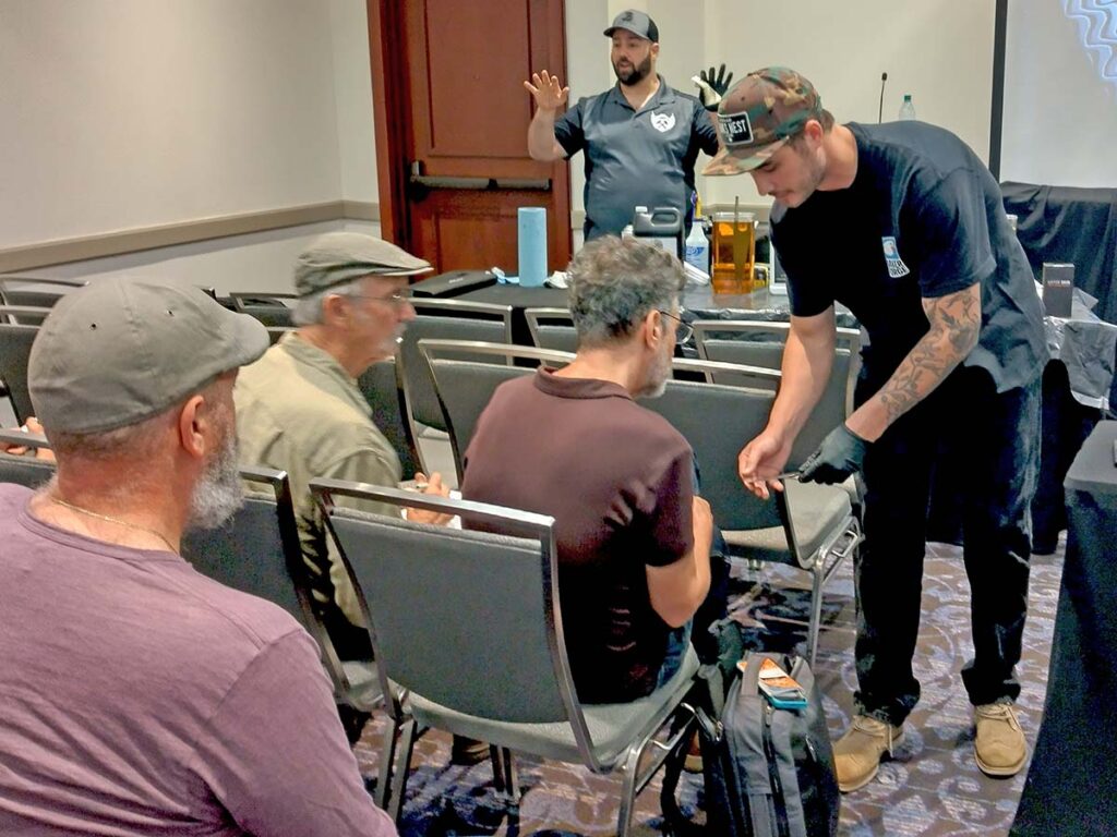 Jordan Berthelot discusses next-level damascus etching while Greyson Weltyk shows a student a result of the process during one of many BLADE University classes.