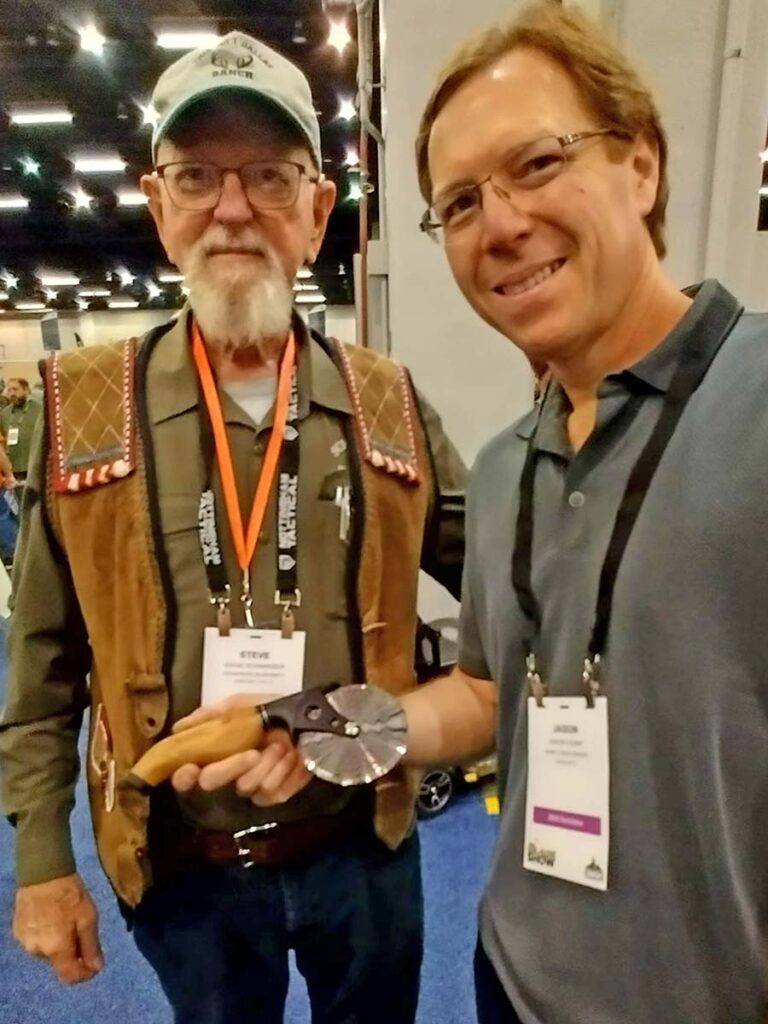 Jason Yount displays his damascus pizza cutter under the watchful eye of BLADE Magazine Cutlery Hall-of-Fame® member Steve Schwarzer. Steve called it the best BLADE Show in a few years.