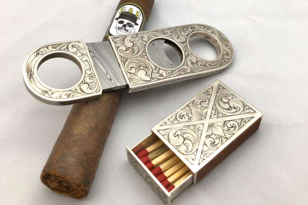  An engraved silver cigar-cutter-and-match-box set by Travis Payne engraved by Matt Litz for relaxing with a puff among friends would round out the author’s dream study. (Matt Litz image)