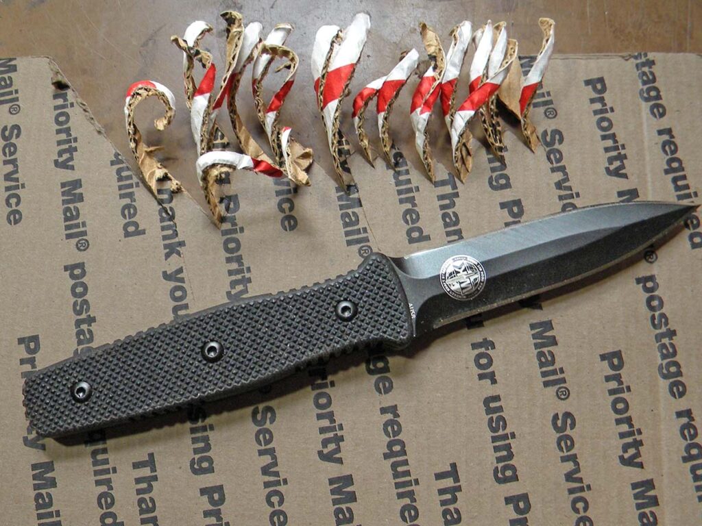 The dagger quickly sliced through cardboard without any problems. The cut ends had a full curl to them because of the grind, which the author expected.