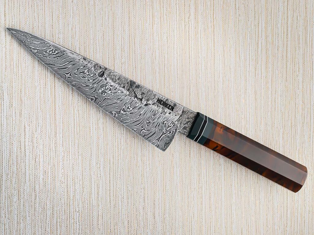 Eric Hemker uses synthetic tortoise shell for the wa handle of his chef’s knife. The flat-ground 7.785-inch blade is a damascus of 1084 carbon and 15N20 nickel-alloy steels. The spacers are green, black and white G-10. Overall length: 14 inches. (SharpByCoop image)