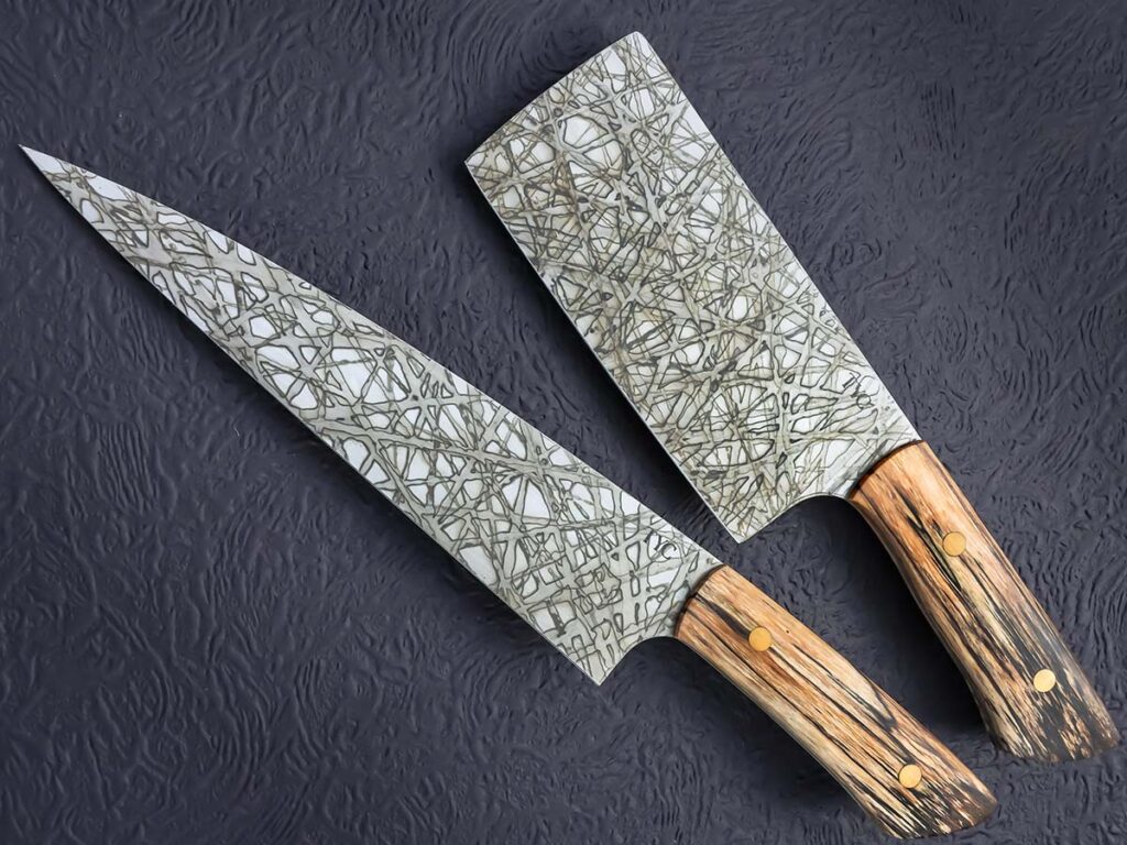 Given the amount of steel and the need to pay attention to minutia is what Bill Tyc figures steers most makers away from cleavers. Tyc achieves an intricate pattern on his cleaver-chef’s knife set through a simple mustard patina, but applied with a straight edge for a pattern he calls “Lines of Insanity.” (SharpByCoop image)