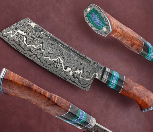 Robert Wayman quips that he packed a lot into his 14-inch pattern damascus cleaver, mainly in the handle. The grip features a damascus collar, stainless steel and G-10 spacers, cross-cut carbon fiber, green malachite and blue coral accents, stabilized amboyna burl, and a damascus butt cap with stainless mounting pins inset with blue coral, framed with green malachite. (SharpByCoop image)