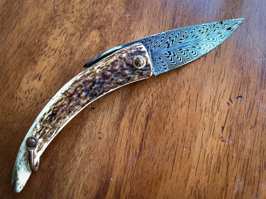 While David Lisch doesn't feel he's hit the limits of his Mountain Man folder, the style of knife is striking with its feather damascus blade set in stag-tip handle. Copper hardware and pivot give the knife its antediluvian look, while the flowing pattern of the blade anchors it in modern forge techniques. (David Lisch image)